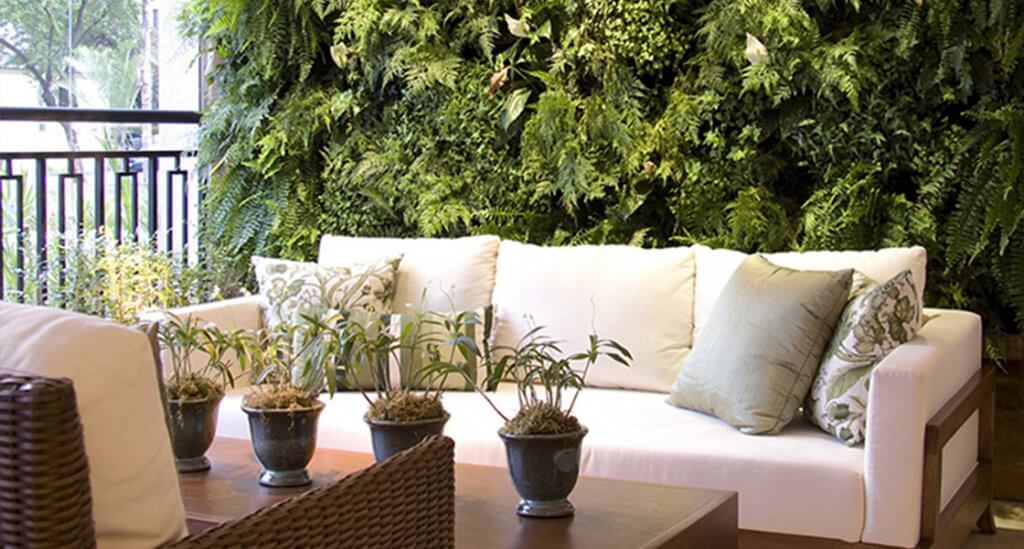 sofás brancos cercados por plantas demonstram que paisagismo é tendência como decoração para sacadas gourmets