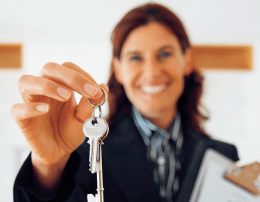 corretora segura em sua frente as chaves de um novo apartamento, simbolizando as dicas que só um corretor de imóveis pode dar