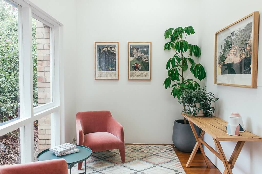 Ambiente interno decorado com plantas, móveis e quadros feitos com materiais naturais.